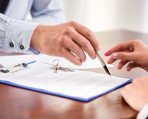 Young woman is signing financial contract with male realtor. Close-up.