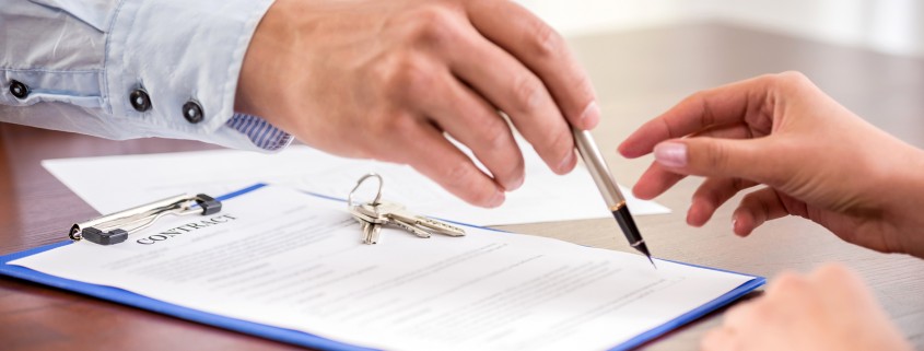 Young woman is signing financial contract with male realtor. Close-up.
