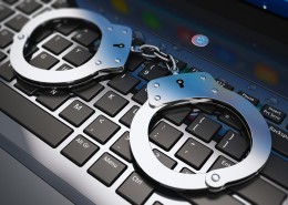 Cyber crime, online piracy and internet web hacking concept: macro view of metal handcuffs on laptop notebook keyboard with selective focus effect